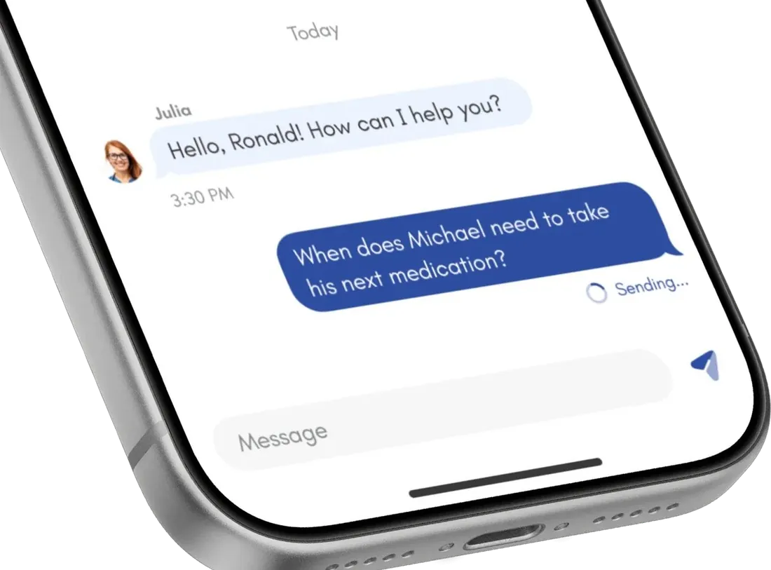 Close-up of a phone showing a chat with Julia: 'Hello, Ronald! How can I help you?' followed by the question 'When does Michael need to take his next medication?'